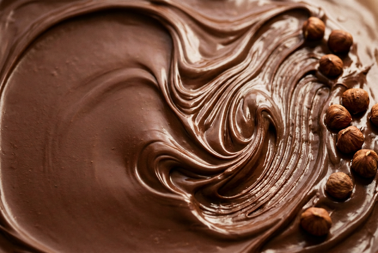 A glossy swirl of chocolate hazelnut spread with whole hazelnuts